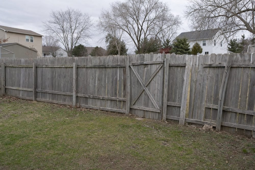 Old, weathered, leaning wood fence before replacement in Fayetteville, NC